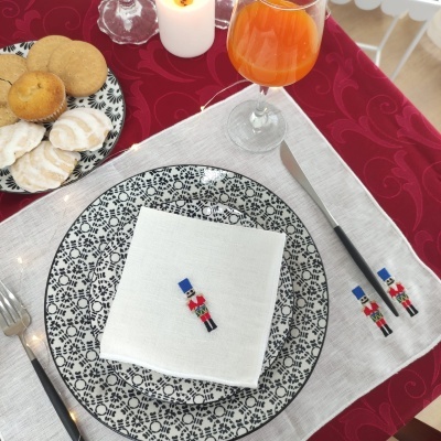 Mesa posta com prato preto e branco, talheres decorados, guardanapo branco e copo com bebida laranja