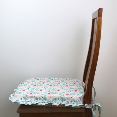 Cadeira de madeira com almofada floral branca, verde e vermelha