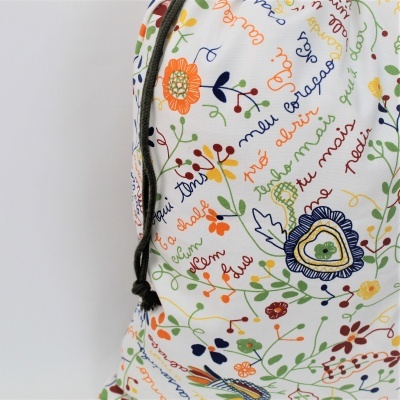 Mochila branca com padrão floral colorido e textos escritos em várias cores.