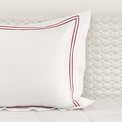 Travesseiro branco com bordas bordô e cabeceira texturizada branca