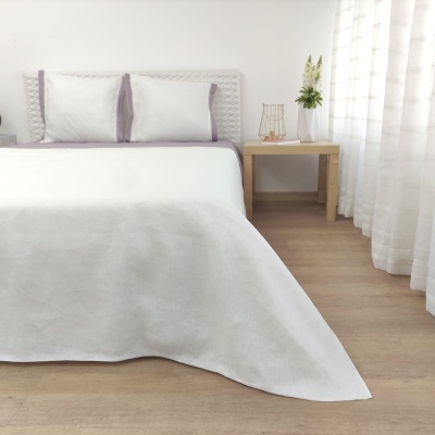 Cama de casal com roupa de cama branca e detalhes lilás em quarto minimalista