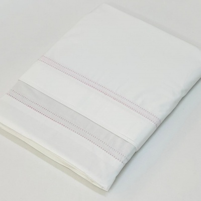 Lençol branco com detalhes decorativos dobrado sobre superfície branca