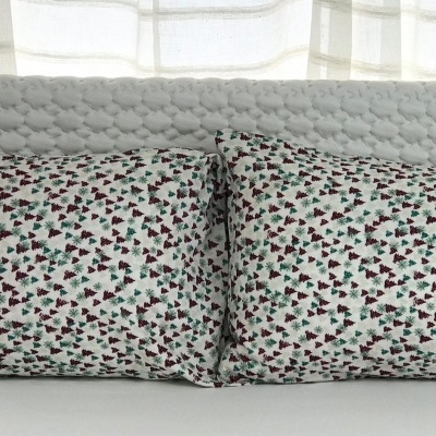 Dois travesseiros florais retangulares junto a cabeceira acolchoada cinza