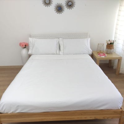 Cama de madeira com lençóis brancos e decoração com flores e espelhos na parede