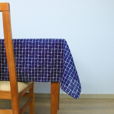 Toalha de mesa azul com padrão de grelha branca sobre mesa de madeira clara e cadeira