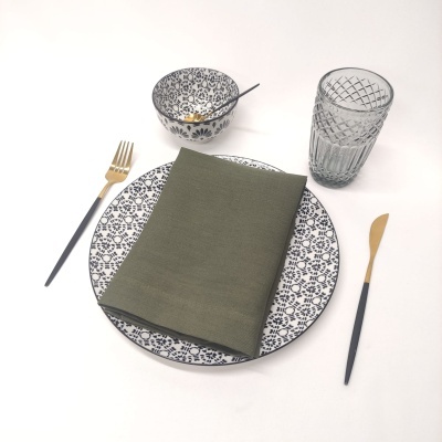 Conjunto de jantar com prato floral, talheres dourados e pretos, copo e tigela com padrão geométrico