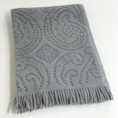 Manta cinzenta com padrão decorativo e franjas
