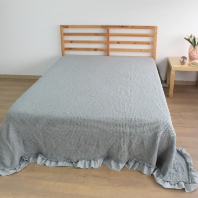 Cama com manta cinzenta e cabeceira de madeira clara