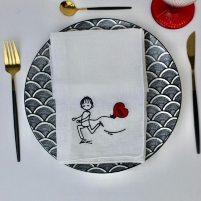 Conjunto de pratos com padrão de escamas, guardanapo branco com desenho e talheres dourados e pretos