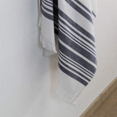 Manta ou toalha branca com riscas azuis pendurada numa parede.