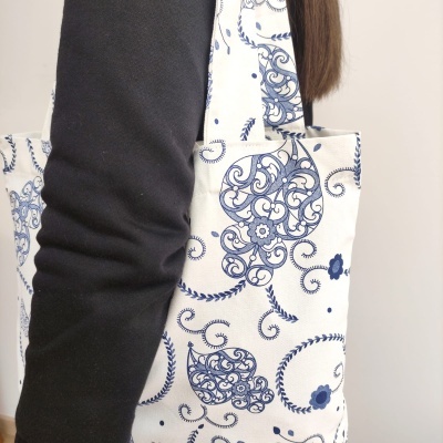 Mala de tecido branca com padrão azul floral usada ao ombro