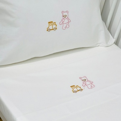 Conjunto de roupa de cama branco com bordados de ursinho e carrinho.