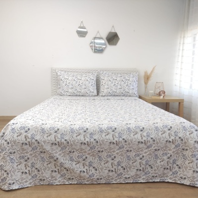 Cama com colcha e almofadas estampadas em padrão floral cinza e azul claro