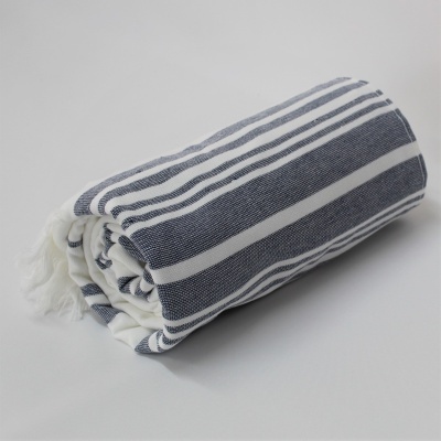 Toalha ou manta com riscas azuis e brancas enrolada num fundo cinzento claro