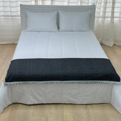 Cama de casal com edredom branco, almofadas brancas e manta preta texturada
