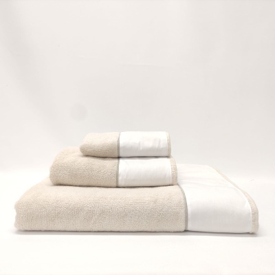 Três toalhas bege com faixa branca e borda dourada empilhadas