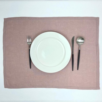 utensílios de mesa numa disposição sobre um individual rosa e fundo branco