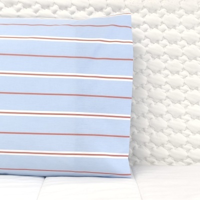 Almofada azul clara com riscas brancas e castanhas em sofá branco texturizado