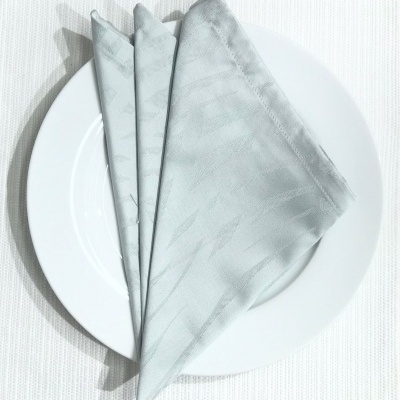 Guardanapo cinza claro dobrado num prato branco