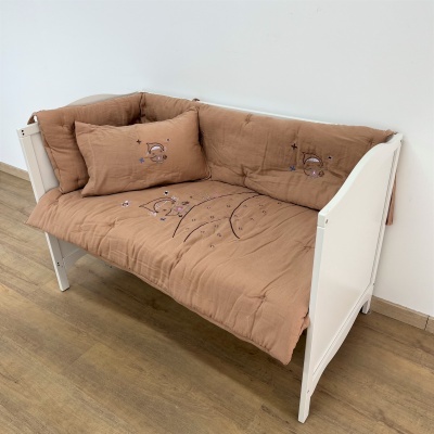 sofá branco com almofadas castanho claro com bordados de estrelas e planetas