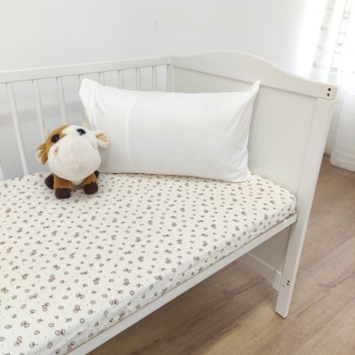 Berço branco com colchão estampado e peluche de vaca