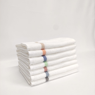 Sete toalhas de mão brancas empilhadas com padrões quadriculados coloridos na bainha.