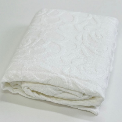 Manta ou toalha branca com padrão floral em relevo dobrada