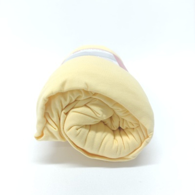 Roupa de bebé amarela enrolada sobre fundo branco