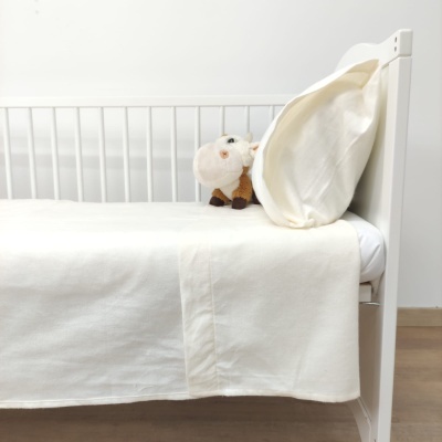 Cama branca de criança com roupa de cama branca e peluche de ovelha