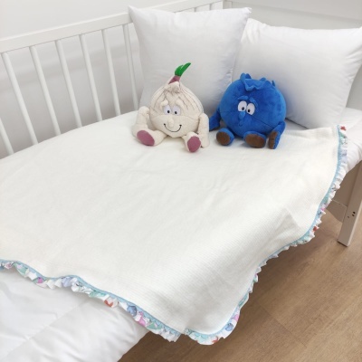 Cama de bebé branca com manta branca e duas peluches em cima