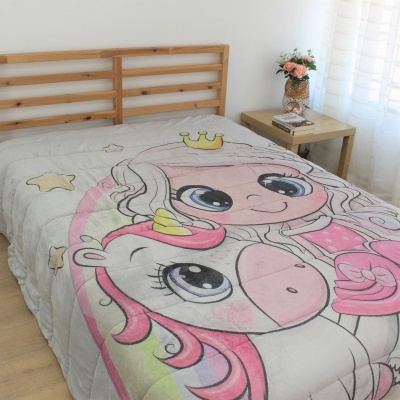 Cobertor infantil colorido com menina e unicórnio numa cama de madeira clara