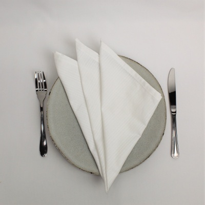 Conjunto de jantar com prato cinza, guardanapo branco, garfo e faca prateados