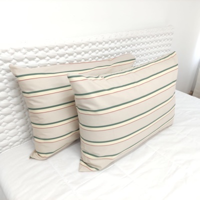 Duas almofadas riscas verdes vermelhas bege em cama branca com cabeceira texturada