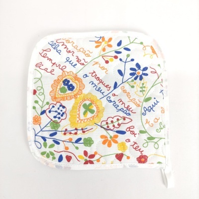 Pano de cozinha branco com padrão colorido de flores e corações e texto manuscrito