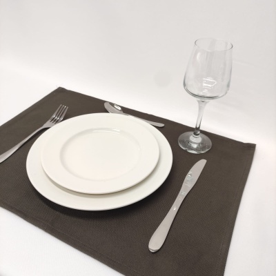 Conjunto de mesa com pratos brancos, talheres de metal, guardanapo castanho e copo de vinho transparente.