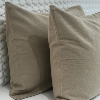 Duas almofadas bege sobre superfície branca com padrão texturizado