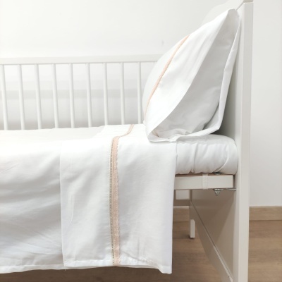 Cama de solteiro branca com roupa de cama branca e faixa rosa clara