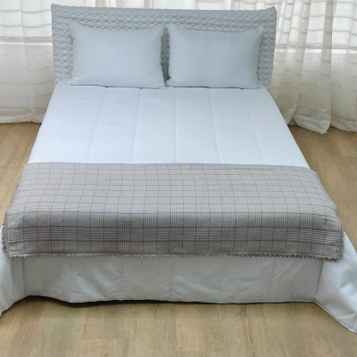 Cama com cabeceira cinza claro e manta cinza em cama com edredão branco