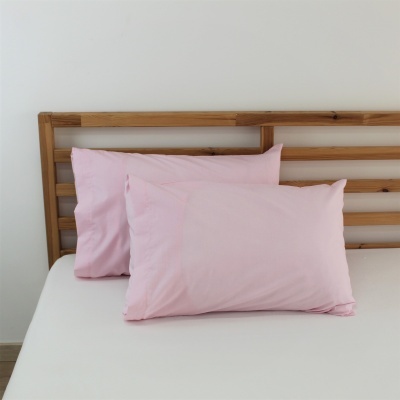 Duas almofadas cor-de-rosa claras em cama com cabeceira de madeira