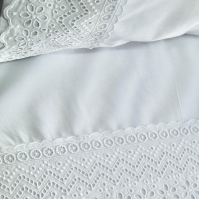 Lençol e fronha brancos com bordado floral e geométrico em tecido
