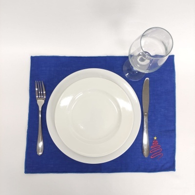Jogo americano azul com bordado de árvore de Natal, prato branco, talheres de metal e copo de vidro