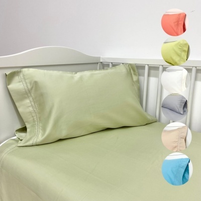 Conjunto de cama verde claro sobre cama branca com amostras de cores ao lado