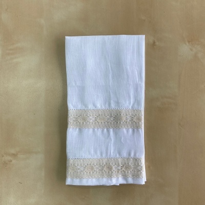 Guardanapo branco com renda bege bordada sobre superfície bege