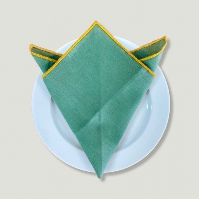 Guardanapo verde com borda amarela dobrado sobre prato branco