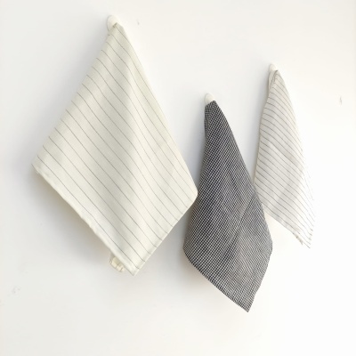 Três panos de cozinha com riscas pendurados numa parede branca.