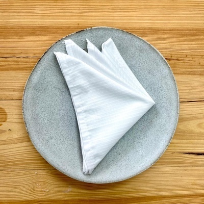 Prato cinza com guardanapo branco sobre mesa de madeira clara