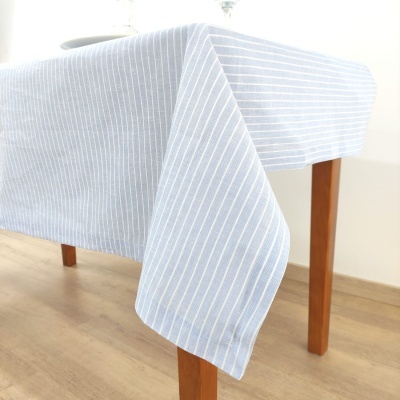Toalha de mesa azul claro com riscas brancas finas sobre mesa de madeira