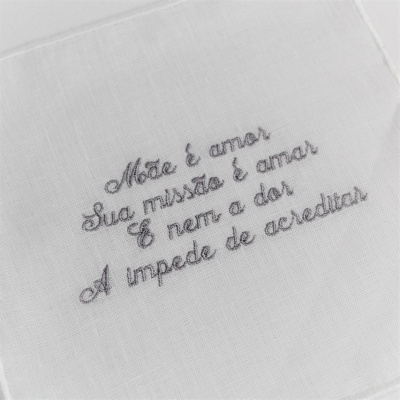 Pano branco com bordado cinzento com frase em português.