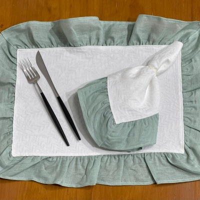 Guardanapo e base para pratos em tecido com talheres numa mesa de madeira