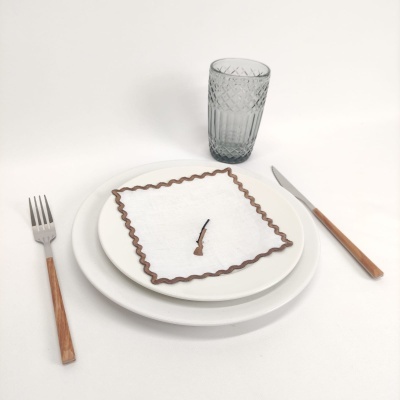 Conjunto de pratos, guardanapo, talheres com cabo de madeira e copo texturizado em mesa branca